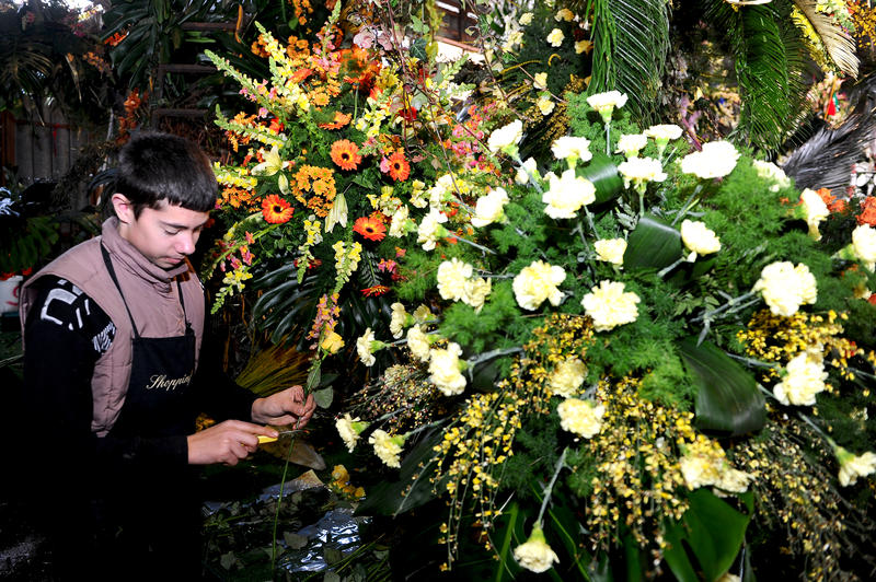 Fleuriste s'afférant à la confection d'un char de Bataille de Fleurs en atelier à Nice